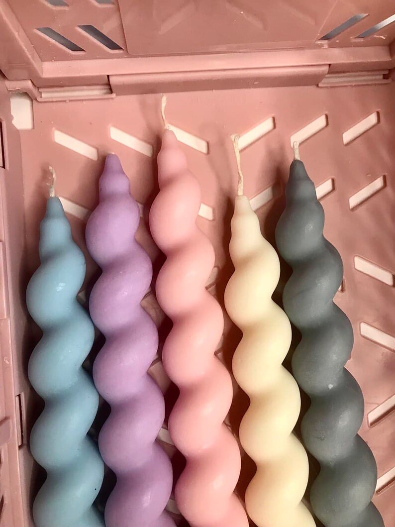 May include: Five spiral candles in a variety of colors, including light blue, lavender, pink, cream, and gray. The candles are arranged in a row and are all the same size.