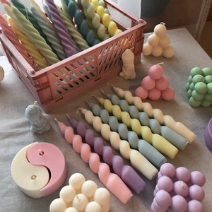 May include: Assortment of colorful candles in various shapes and sizes.  The candles are made of wax and have a variety of colors, including pink, blue, yellow, and green.  The candles are arranged in a basket and on a table.