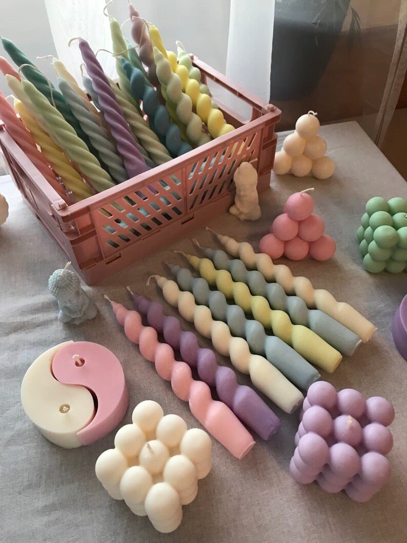 May include: Assortment of colorful candles in various shapes and sizes.  The candles are made of wax and have a variety of colors, including pink, blue, yellow, and green.  The candles are arranged in a basket and on a table.