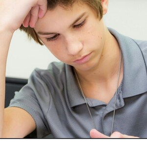 May include: A person with light brown hair wearing a grey polo shirt and a silver chain necklace, looking down with a hand resting on their forehead. Below the image, the text reads: The Struggle is Real! The overall composition is focused.
