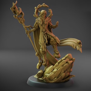 Può includere: Una statuetta dettagliata, color marrone chiaro, di un personaggio fantasy, forse un elfo o un mago, in piedi su una base rocciosa. La figura è adornata con abiti intricati, un mantello fluente e un bastone. Una struttura a forma di alone circonda la testa.
