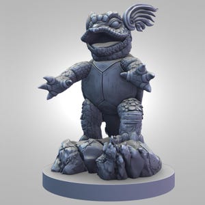 May include: A gray, stylized sculpture of a turtle-like creature with outstretched arms, standing on a rocky base. The creature has a detailed shell, textured skin, and a decorative wing-like element on its head. The sculpture is on a round, light gray base.