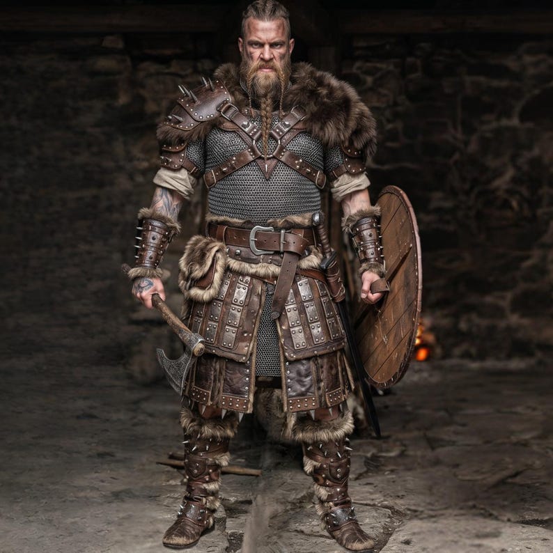 May include: A full-body shot of a person in a Viking warrior costume. The costume includes brown leather armor, a fur collar, and a chainmail shirt. The warrior holds an axe in one hand and a wooden shield in the other.