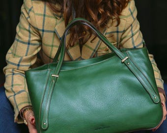 Op de afbeelding: Een grote, getextureerde bosgroene leren tas met twee handvatten, verstevigde zijstiksels en een gestructureerde rechthoekige basis. De tas heeft een gladde afwerking met zichtbare korrel en metalen hardware-accenten.