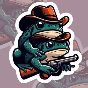 May include: A sticker featuring two green frogs wearing brown cowboy hats. The bottom frog holds a silver revolver. The frogs are stacked on top of each other. The sticker has a white border and a purple background.