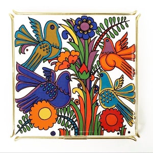 May include: Square decorative tray with a colorful bird and floral design. The birds are in shades of blue, orange, and yellow, set against a white background with a gold-colored metal frame. The flowers are in shades of orange, purple, and blue.