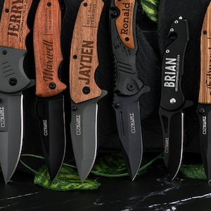 May include: Seven pocket knives with wooden handles and black blades. The handles are engraved with names and dates. The blades are all closed.