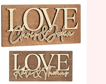 May include: Two wooden signs with the word "LOVE" in large, white letters. The names "Chris & Julia" and "Kate & Thomas" are written in cursive on the signs.