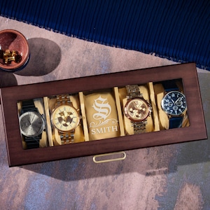 May include: A wooden watch box with a glass top, displaying four watches. The box has a personalized inscription that reads "S SMITH".