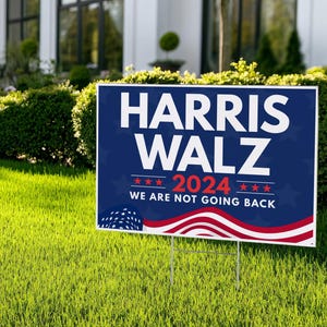 May include: A blue and red political yard sign with the text "Harris Walz 2024 We Are Not Going Back" and a stylized American flag design.