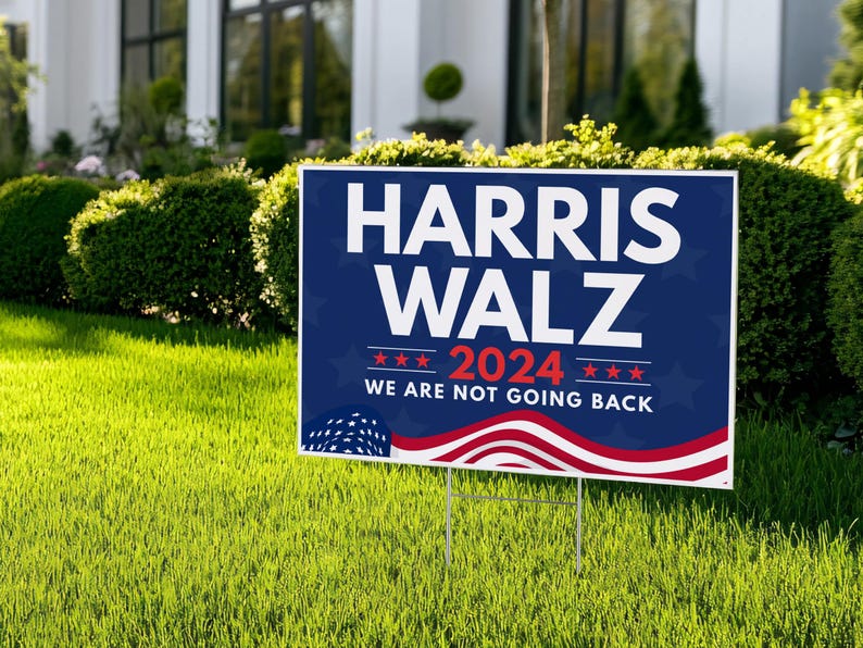 May include: A blue and red political yard sign with the text "Harris Walz 2024 We Are Not Going Back" and a stylized American flag design.