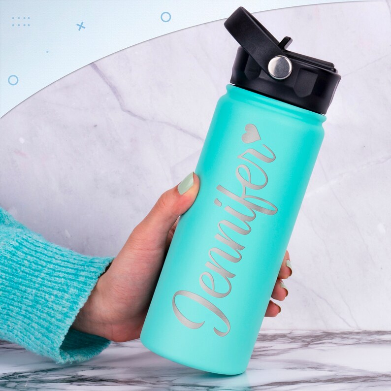 K&ouml;nnte beinhalten: Eine t&uuml;rkisfarbene Wasserflasche mit schwarzem Deckel und einer silbernen Aufschrift "Jennifer" mit einem kleinen Herzsymbol.
