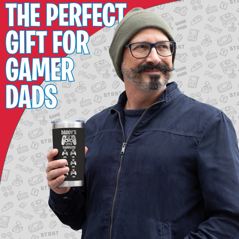 May include: A black stainless steel tumbler with a white design that says "Daddy's Little Teammates" and features a video game controller graphic. The tumbler is being held by a person wearing a blue jacket and a beanie.