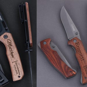 May include: Two personalized pocket knives with wooden handles. The knife on the left has the name "Matthew" engraved on the handle, along with the text "Groomsman 11.07.2025". The knife on the right has the name "Emmett" engraved on the handle, along with the text "Best Man 21.07.2025".