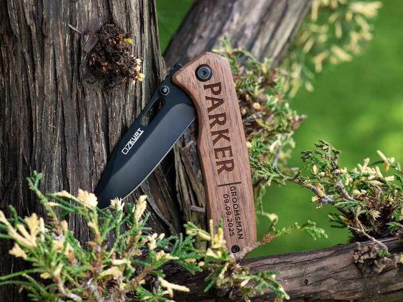 May include: A black pocket knife with a wooden handle engraved with the name "Parker" and the text "Groomsman 09.09.2025".