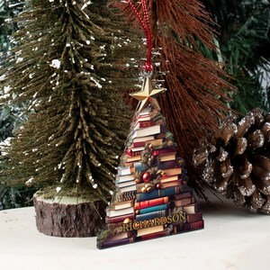 May include: A Christmas tree ornament shaped like a stack of books with a gold star on top. The ornament is decorated with red and green ornaments and has the word "RICHARDSON" at the bottom.