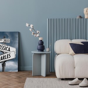 Op de afbeelding: Een canvas print met een straatnaambord met de namen "Jessica" en "Charles" en de tekst "Est. 2023". Het bord is tegen een bewolkte lucht.