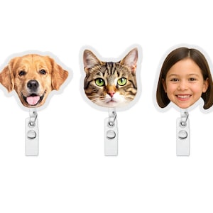 May include: Three retractable badge holders with white plastic clips. The badge faces feature a golden retriever dog, a tabby cat, and a smiling girl's face. The backgrounds are white.