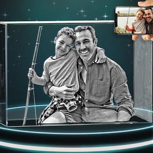May include: A black and white 3D crystal cube with a photo of a father and son smiling and holding a fishing rod. The crystal cube is on a black pedestal with a blue light ring.