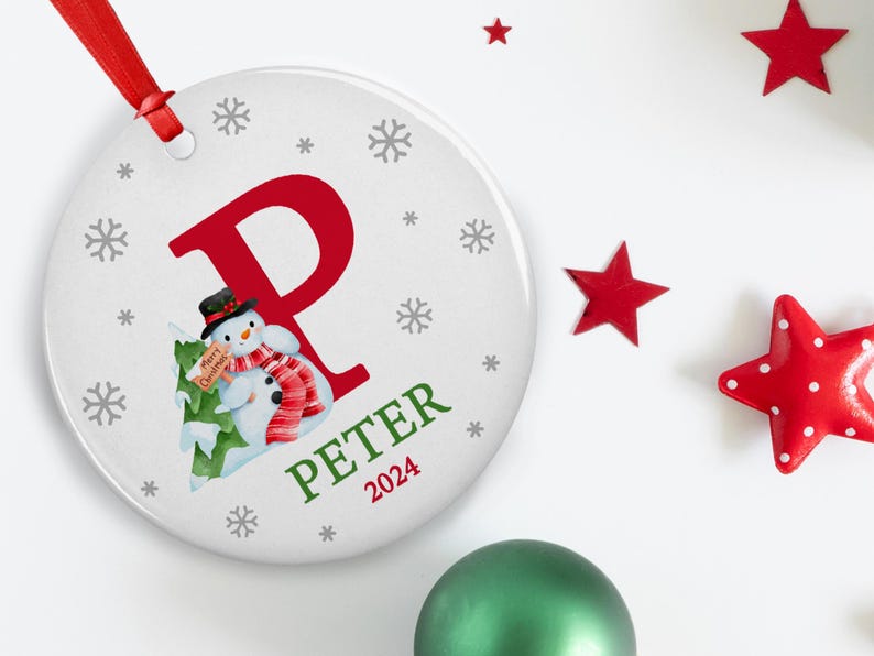 May include: White ceramic Christmas ornament with a red letter P, a snowman holding a "Merry Christmas" sign, and the name "Peter" with the year "2024" below.