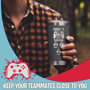 May include: A gray stainless steel tumbler with a black and white design that says "Daddy's #1 Little Teammates" with a video game controller graphic and the names Ashton and Mac.