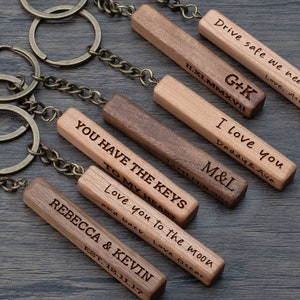 May include: A set of six wooden keychains with different engraved messages. The keychains are made of light and dark brown wood. The messages on the keychains include 