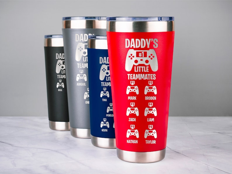 May include: Four stainless steel tumblers with a red, blue, gray, and black finish. Each tumbler features a laser engraved design of a video game controller with the text "Daddy's Little Teammates" and a list of names.