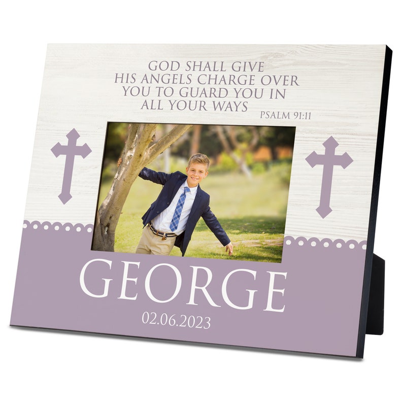 May include: A lavender-colored photo frame with a white woodgrain background. The frame has a photo of a young boy in a suit and tie. The frame has a cross on each side and the text "GOD SHALL GIVE HIS ANGELS CHARGE OVER YOU TO GUARD YOU IN ALL YOUR WAYS PSALM 91:11". The frame also has the name "GEORGE" and the date "02.06.2023".