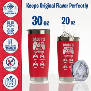 May include: Red 30 oz and 20 oz stainless steel tumblers with a gamer theme. The tumblers feature a silver video game controller with the text "Daddy's #1 Little Teammates" and the names James, Cameron, Bobby, and Steve.