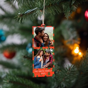 K&ouml;nnte beinhalten: Ein roter und gr&uuml;ner Weihnachtsanh&auml;nger mit zwei Fotos eines Paares. Der Anh&auml;nger tr&auml;gt den Text "THE SMITH FAMILY 2023" am unteren Rand.
