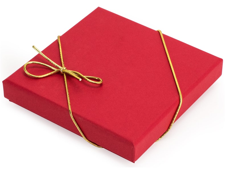 May include: A square red gift box with a matte finish, wrapped with a thin, metallic gold cord tied into a decorative bow on the top surface. The box features sharp, clean edges and a flat lid, presenting a simple and uniform appearance.