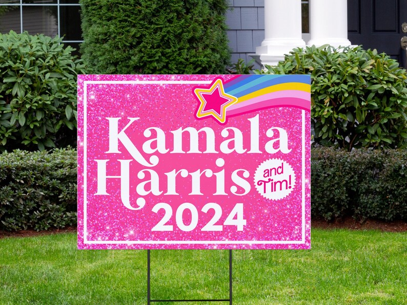 May include: Pink and white yard sign with glitter background. The sign says "Kamala Harris and Tim! 2024" with a rainbow and star graphic.