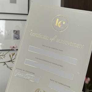 Könnte beinhalten: Eine Leistungsurkunde mit goldfarbenen Buchstaben und Akzenten. Der Text lautet "Leistungsurkunde" und enthält Platz für den Namen des Empfängers und das Datum. Das Zertifikat hat das "IC"-Logo.