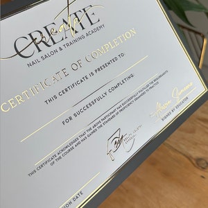 May include: A certificate of completion from Create Nail Salon & Training Academy. The certificate has a black border and gold foil lettering. The text includes "Certificate of Completion" and "Signed by Educator".