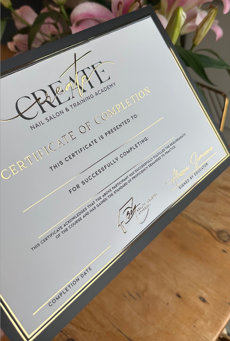 May include: A certificate of completion from Create Nail Salon & Training Academy. The certificate has a black border and gold foil lettering. The text includes "Certificate of Completion" and "Signed by Educator".