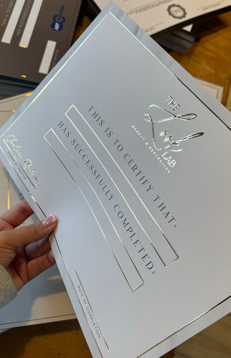 May include: A white certificate with gold foil accents. The text reads "THE LUX LAB BEAUTY & AESTHETICS" and "THIS IS TO CERTIFY THAT: HAS SUCCESSFULLY COMPLETED:" The certificate is signed by a mentor.