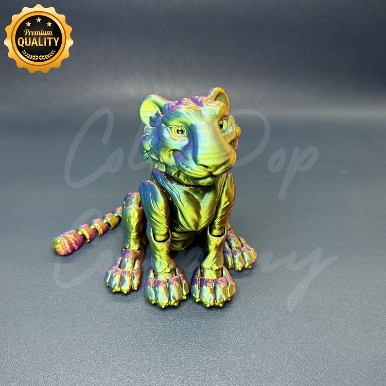 May include: A small, iridescent green and purple tiger figurine with a textured surface. The figurine is sitting on a gray surface.