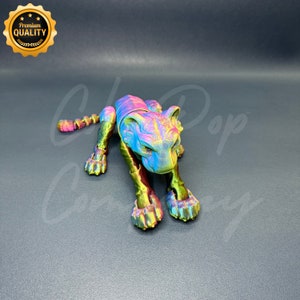 May include: A colorful, iridescent, articulated toy tiger figurine. The tiger is in a crouching position with its head lowered and its paws extended. The toy is made of plastic and has a metallic finish.