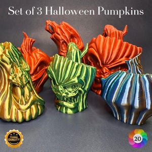 May include: A set of three Halloween pumpkins in various colours. One is gold and green, another is green and yellow, and the third is blue and brown. The pumpkins have carved faces and textured surfaces. The text "Set of 3 Halloween Pumpkins" is at the top.