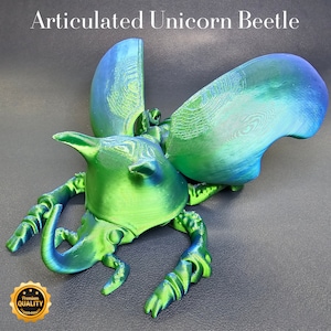 May include: An articulated unicorn beetle figurine, green and blue in colour. The beetle has iridescent wings and a horn on its head. The figurine is made of plastic and is approximately 12.5 cm long.