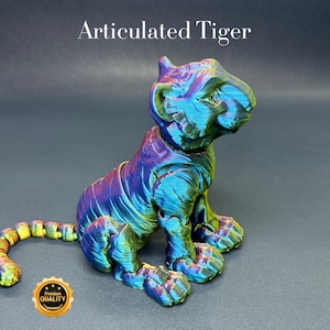 May include: A 3D printed articulated tiger figurine with a iridescent finish. The tiger is sitting with its tail curled behind it. The figurine is made of plastic and has a detailed design.