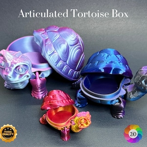 May include: Articulated tortoise boxes in iridescent colours, including blue, purple, and red. The boxes are open, revealing their interior. The text "Articulated Tortoise Box" is at the top of the image. The boxes are 3D printed.