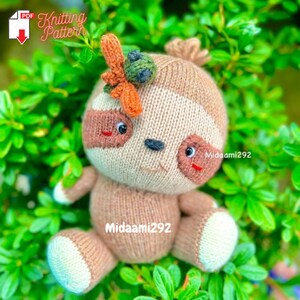 May include: Knitted sloth toy with brown and white fur, sitting on green foliage. The sloth has a flower on its head and black eyes. The text "Knitting Pattern" is visible in the top left corner of the image.