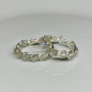 May include: Two silver rings with a braided wire design and grey labradorite gemstones.