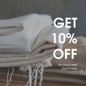 Puede incluir: Una pila de tela blanca y beige doblada con el texto "GET 10% OFF on your next purchase!" en letras blancas.