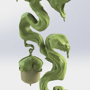 Puede incluir: Una escultura verde impresa en 3D de una vid con dos cabezas de serpiente y una bellota en la parte inferior. La vid est&aacute; enroscada y retorcida, y las cabezas de serpiente tienen la boca abierta y dientes afilados. La bellota es marr&oacute;n y tiene una tapa verde. La escultura est&aacute; firmada "By Miss Messy Mia".