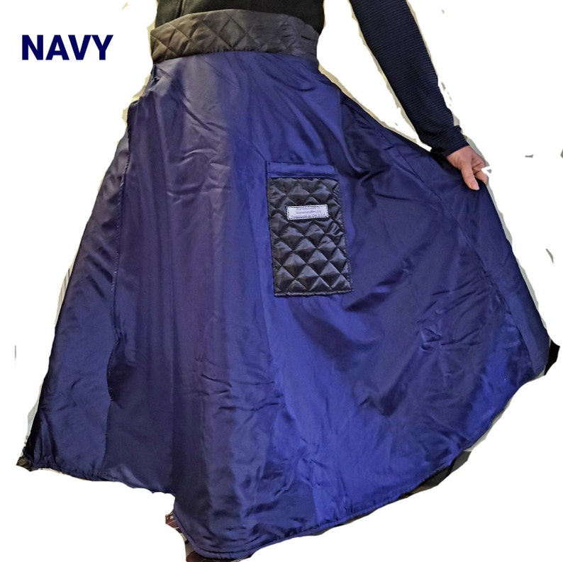 Pode incluir: Uma saia acolchoada azul marinho com uma cintura preta e um bolso acolchoado preto no lado direito. A saia &eacute; ampla e fluida.