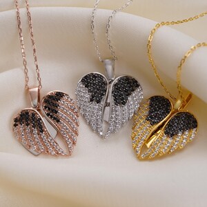 Three ornate necklaces with heart-shaped pendants are displayed on a white fabric background.