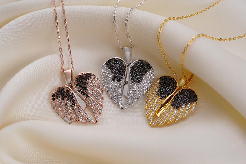 Three ornate necklaces with heart-shaped pendants are displayed on a white fabric background.
