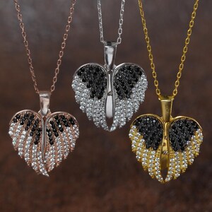 Three heart-shaped pendants with black and white gemstones are displayed against a brown background.
